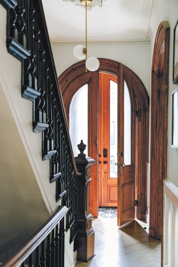 Wooden, arched doorway leads to historic staircase in large foyer