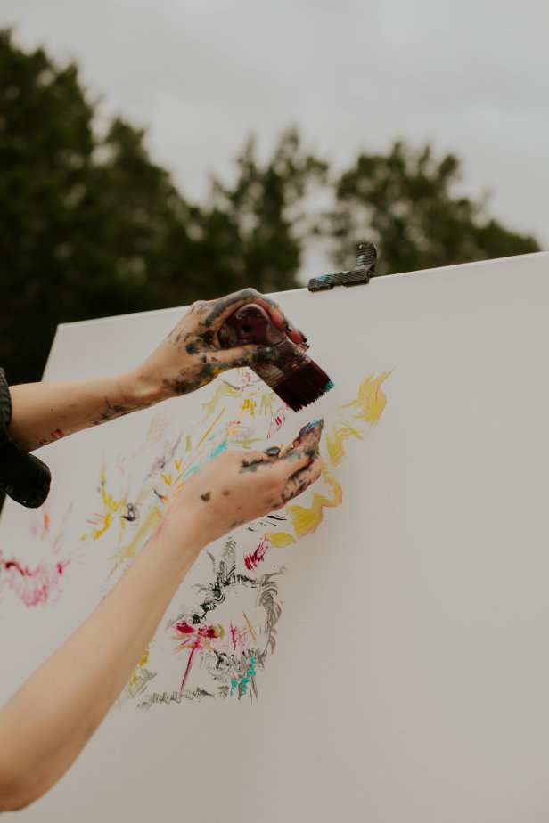 Artist Sarah Kraning splatters yellow paint on her canvas.