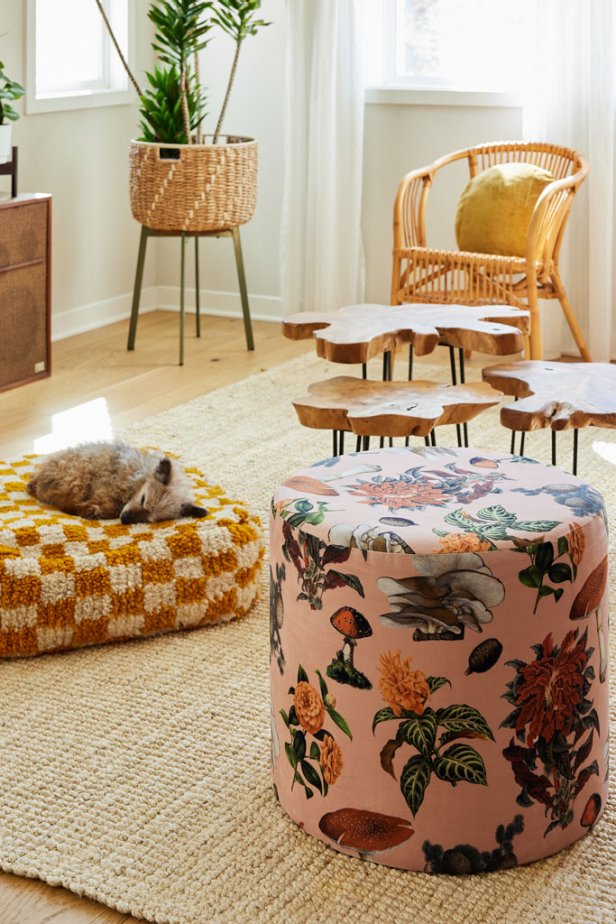 Interior Designer Samantha Santana keeps a neutral home with pops of color in the form of florals and patterns throughout the space while textured items provide visual interest. The ottoman is covered in custom fabric with blush, gold and green colors, and the gold repeats itself in the floor pillow and a throw cushion on a wicker chair. 