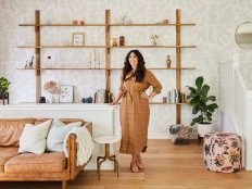 Woman standing next to a half wall in a neutral living room.