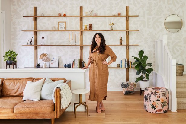 Woman standing next to a half wall in a neutral living room.