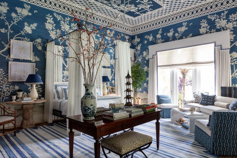 Ornate wallpaper and ceiling treatment, molding and a profusion of color and fabric mark this stunning bedroom designed by Phoebe Howard for the 2024 Kips Bay Decorators Shophouse in Palm Beach  as a modern take on Hollywood Regency.  