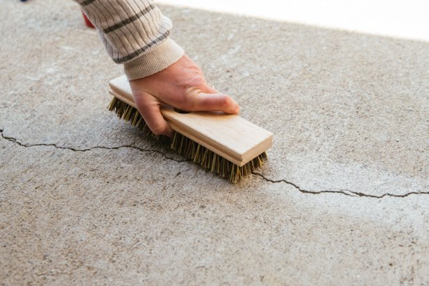 Use a brush to clean dust from the area around the crack in the concrete.