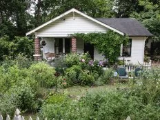 The exterior of a home with brick columns on the front porch and a rewilded garden