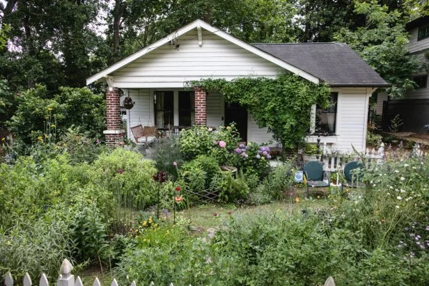 The exterior of a home with brick columns on the front porch and a rewilded garden