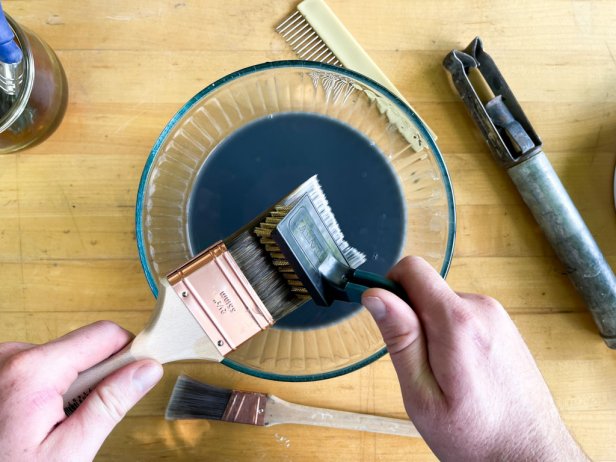 The next step in cleaning a paint brush is to brush dried paint out of the bristles using a soft wire brush.