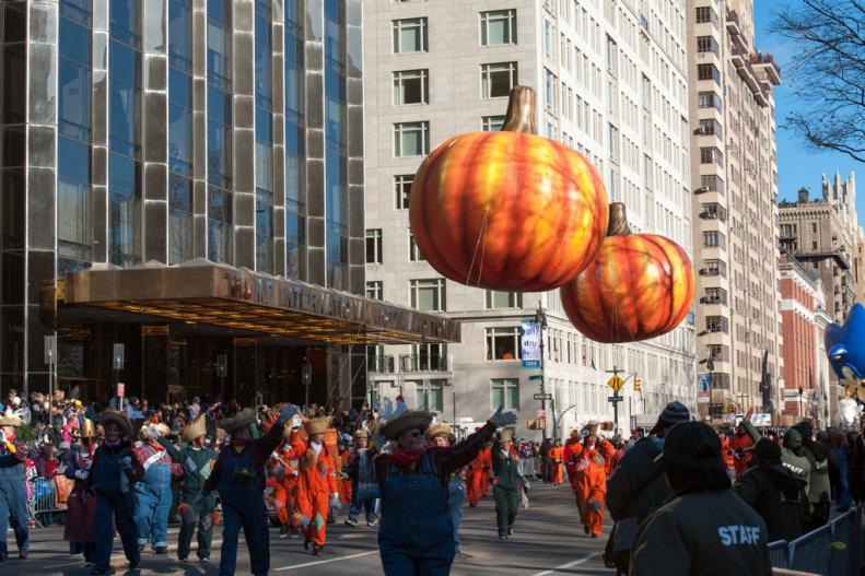 Macy's Thanksgiving Parade in Manhattan with crowds lining the streets and two big pumpkin balloons floating overhead