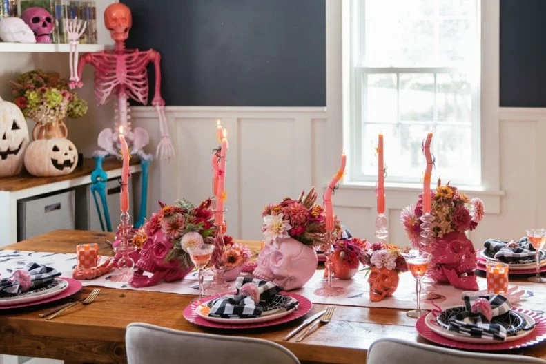 A dining room tablescape with pink skull vases and pink flowers