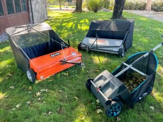 Three Lawn Sweepers Sitting Side by Side on Grass