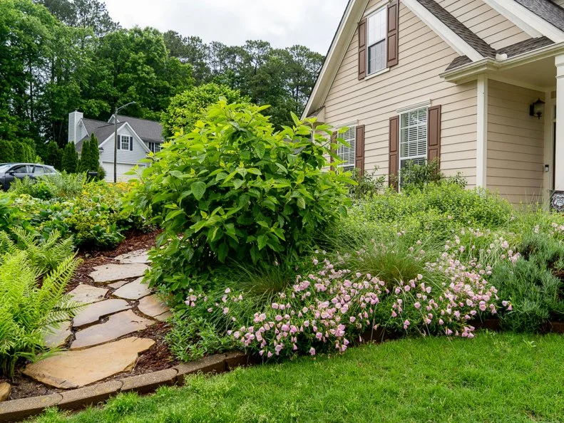 A view of a house with a flagstone path and plants surrounded by mulch.