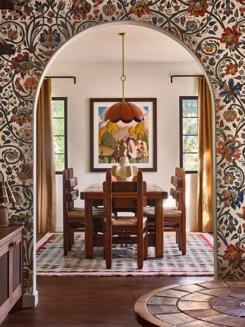 Wallpapered Archway to Neutral Dining Room With Statement Lighting