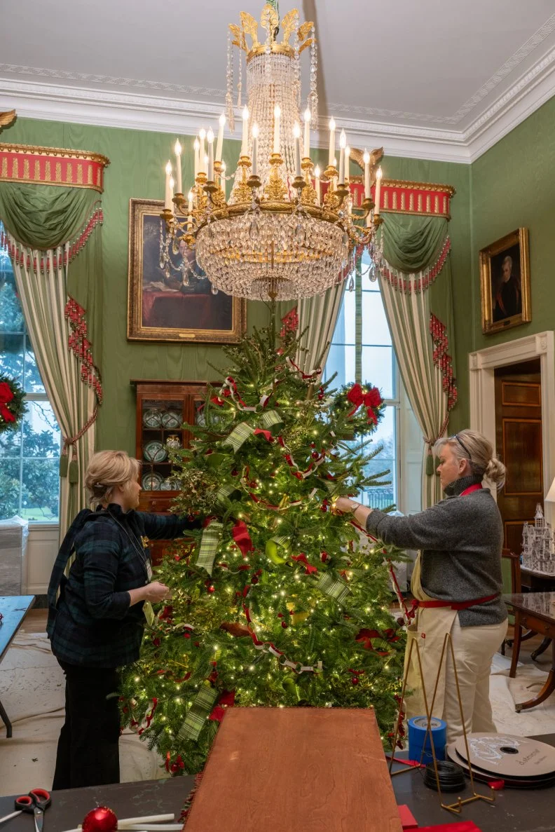 Two volunteers decorate the Green Room Christmas tree for the holidays.