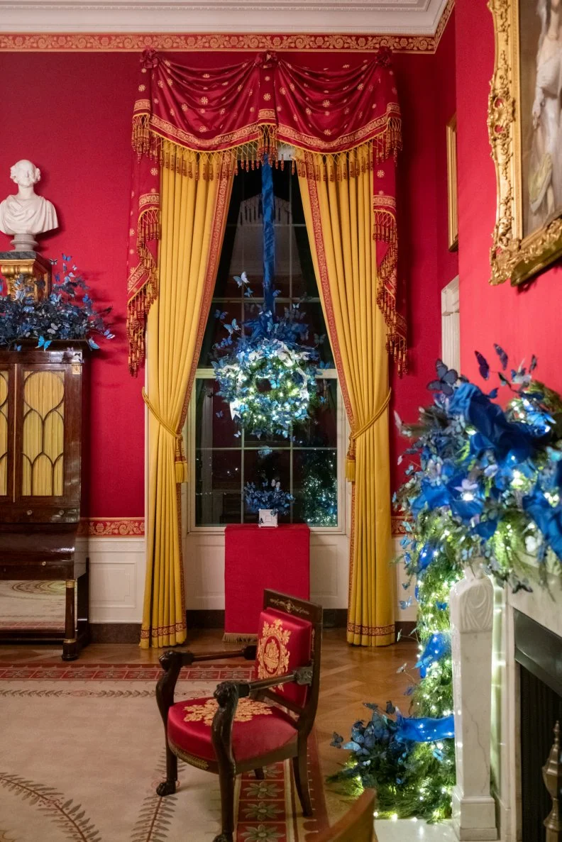 The White House Red Room is even more resplendent with fresh wall fabric that contrasts beautifully with its gold drapes. Cheerful royal blue butterflies decorate the mantle and the window wreaths in the Red Room and offer a tribute to America's foster care community.