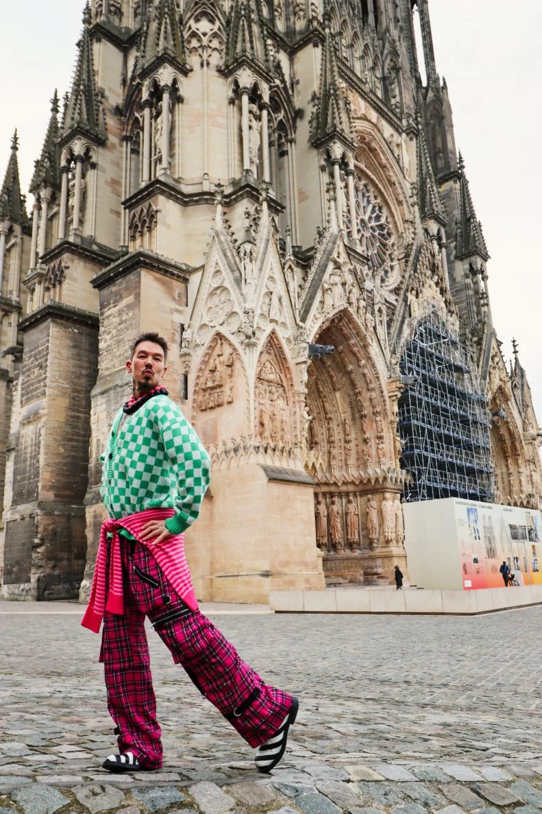 A man striking a pose with the Notre Dame Cathedral behind him
