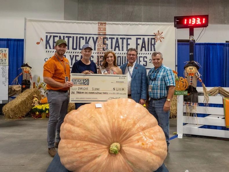 People holding an oversized check awarded for the largest pumpkin at the Kentucky State Fair