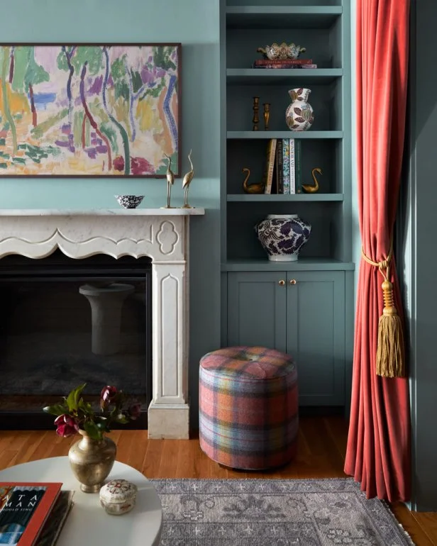 A living room painted blue with salmon drapes and ottoman