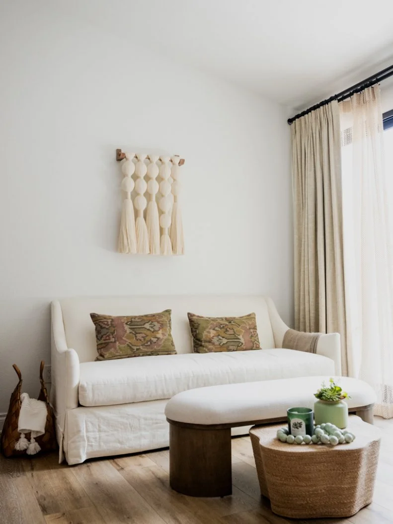 A backdrop of white walls and white furniture allows accessories like a woven wall piece, plants and tapestry pillows to really pop, as in Alison's mini-lounge in her primary bedroom where she often watches television.