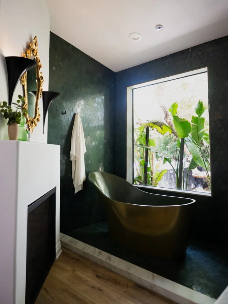 Alison was inspired by Cabo resorts in this spa-like bathroom with a gorgeous gold and green soaking tub and a view of the foliage outside.