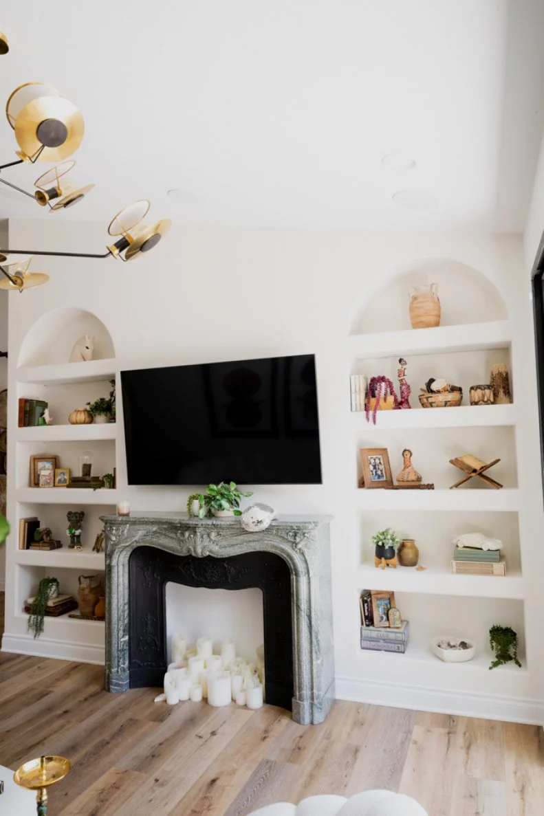 A green marble mantel sourced from France is a statement piece in Alison's living room. Two built-in bookcases with contemporary arched lines provide another space in her home for travel and family mementoes.