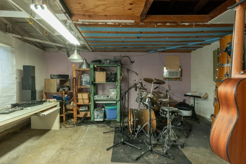 This ramshackle, makeshift music studio in Ken's garage has some obvious flaws, like a definite lack of rock star ambiance. Then there's the fact that beating the skins has been known to leak out of the garage and into the neighborhood notes Ken.