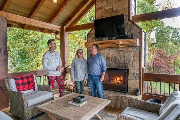 Homebuyers Alicia and Rick Jultak check out the outdoor space alongside David Bromstad at this Blue Ridge, Georgia vacation home featuring a sitting area and fireplace.