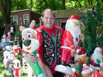 Brandon posing with Christmas blow molds, as seen on Hoarding for the Holidays, Season 1.