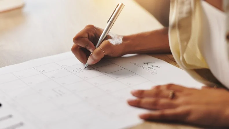 Calendar, writing and hands of person in office for schedule, planning and reminder on paper. Professional, administration and worker with monthly planner for appointment, business notes and deadline