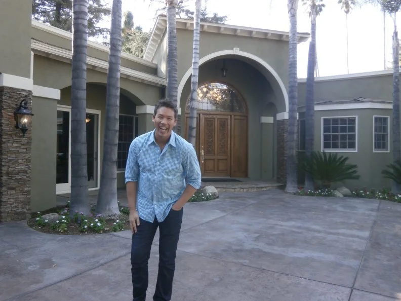 Host David Bromstad standing at the front entrance of Casa de Serenidad property, as seen on My Lottery Dream Home. (portrait)
