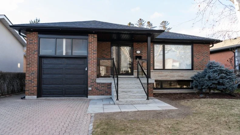 Mike and Janetta's front exterior has been updated with a new garage door, sturdy stone steps, and new aluminum rails - all trim and soffits painted black to match for a stunning update.
