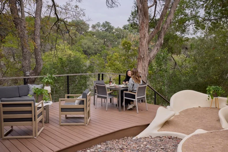Host Sherry Cola and D’Arcy Carden on the Back Porch eating Steak of the Bloomhouse, as seen on Wild Vacation Rentals, Season 1.