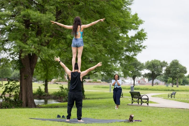 Client's Mark and Anastasia practicing arial tricks in the park as host Noel Collier approaches, as seen on Extreme Buyers Club Season 1