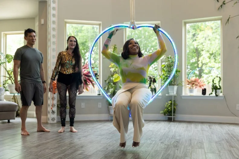 Client's Anastasia and Mark showing host Noel Colliert how to use heir in home aerial silks, as seen on Extreme Buyers Club Season 1