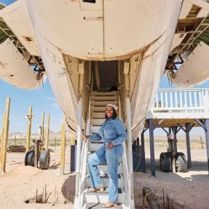 Host Noel Collier poses for a photos in front of the finished airplane house, as seen on Extreme Buyers Club, Season 1.