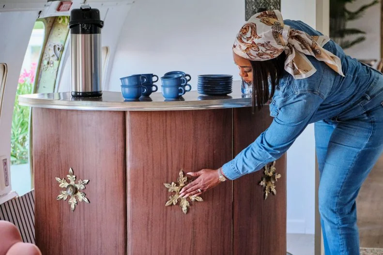 Host Noel Collier admires the detailed trim on the beverage bar at the finished airplane house, as seen on Extreme Buyers Club, Season 1.