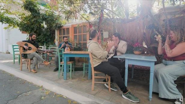 House Hunters Anna & Andreas and Real Estate Agent Dion enjoying Cretan music at the terrace of a cafe