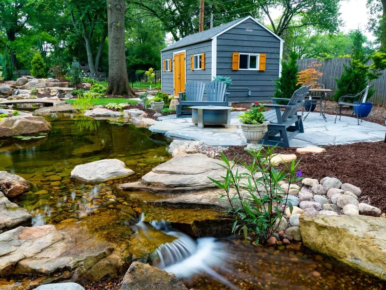 A house with a garden pond, rocks, plants and a flagstone deck