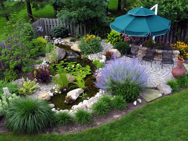 An aerial view of a garden pond with colorful plants and a patio umbrella