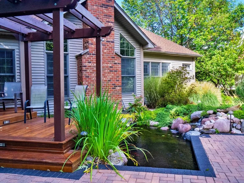 A contemporary-style pond beside a straight-edged patio and deck