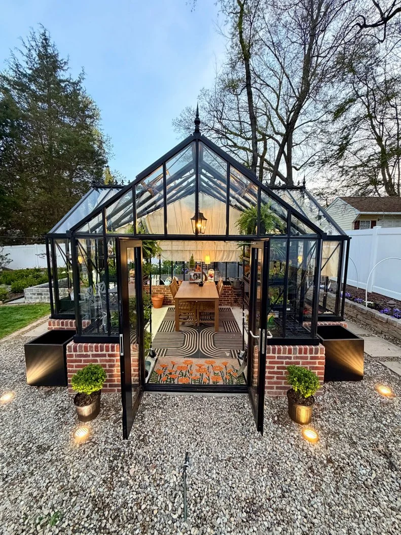 Elegant glass greenhouse exterior with open doors and garden path