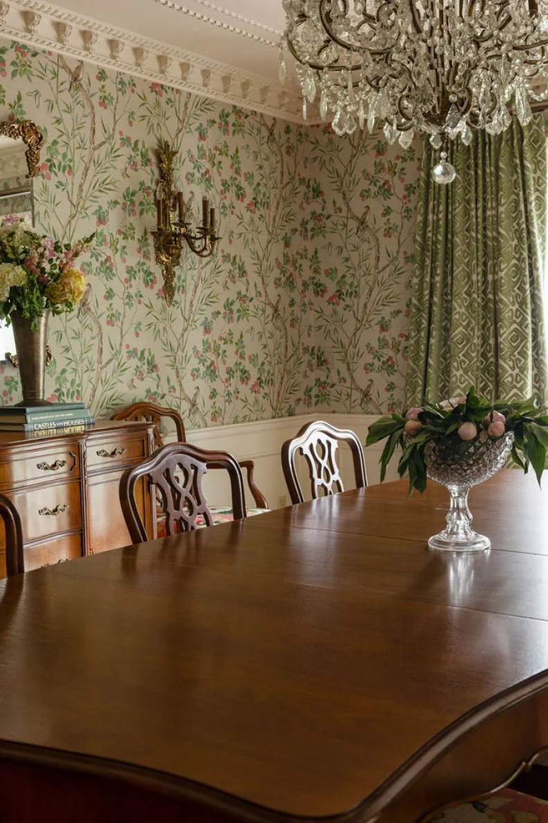 Despite varying prints, the use of green in both the dining room wallpaper and graphic curtains gives the room cohesion.
