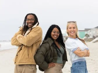 Team Sarah Baeumler’s Angelina and Steven Jacobs celebrate with their mentor after winning the living room renovation, as seen on Battle on the Beach, Season 5.
