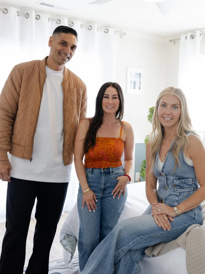 Judges Tristyn and Kamohai Kalama pose in Team Sarah’s guest bedroom with mentor Sarah Baeumler, as seen on Battle on the Beach, Season 5.