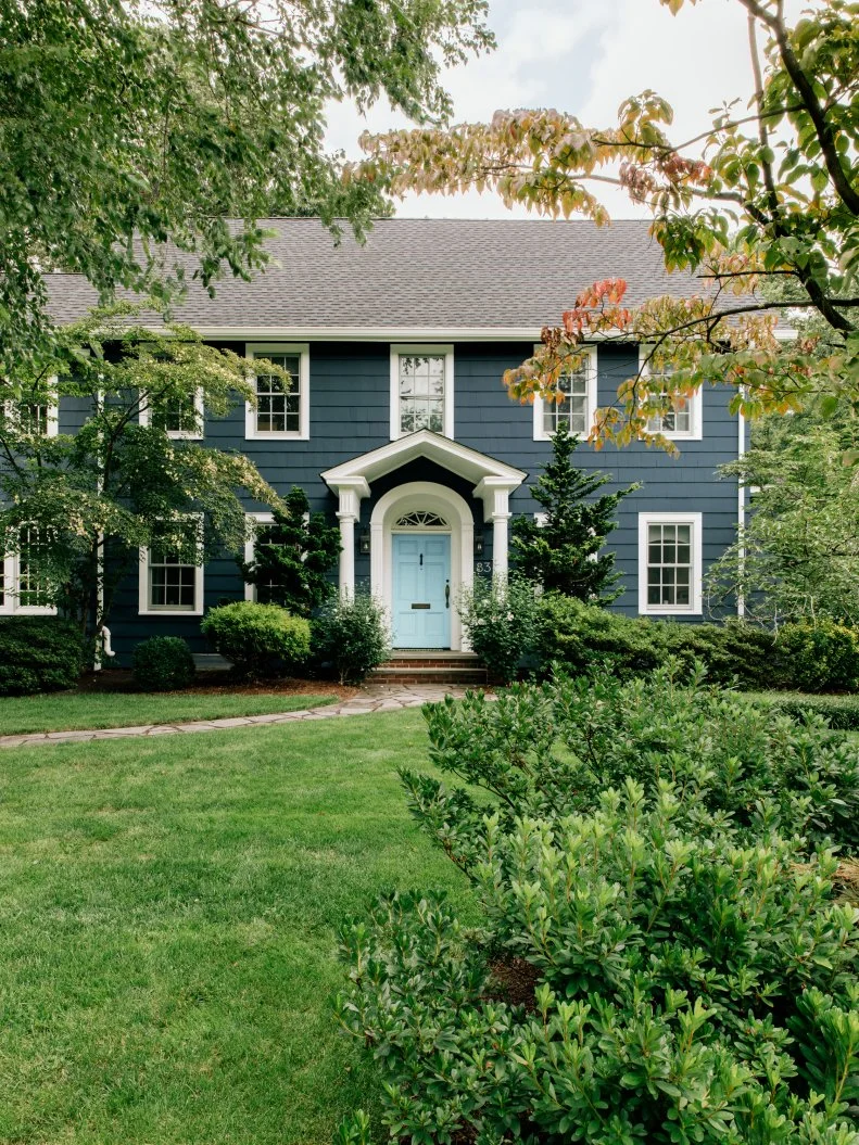 HGTV Magazine featured this class dark blue Colonial home with a light blue front door and white trim and columns.