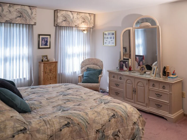 bedroom dresser and mirror with chair in corner in main bedroom as seen on Totally 90s House, Season 1.