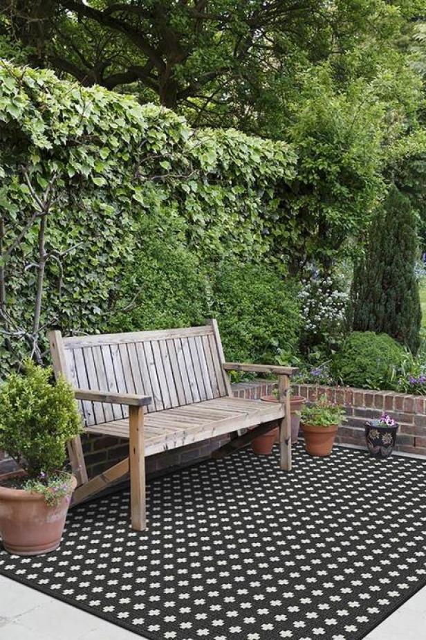 A typical English back garden in the UK, with flag stone patio and wooden bench patio furniture