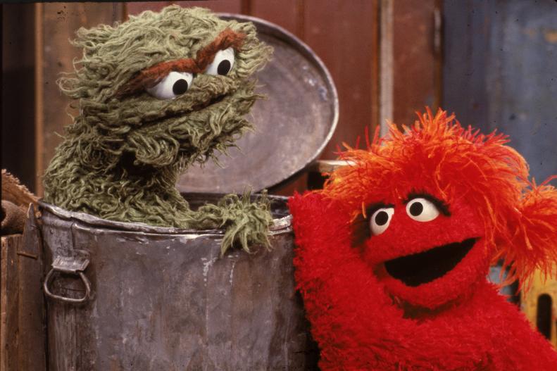 A red muppet visits Oscar the Grouch, inside his garbage can, in a scene from the children's television program 'Sesame Street,' 1980s. (Photo by Children's Television Workshop/Courtesy of Getty Images)