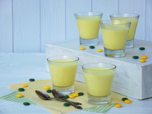 Yellow dessert Junket from milk and rennet extract with turmeric in glasses on light background. Jelly-like pudding made from sweet cottage cheese. Healthy food. Space for text.