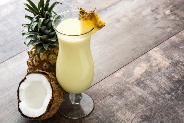 Piña Colada cocktail and pineapple fruit on wooden background.