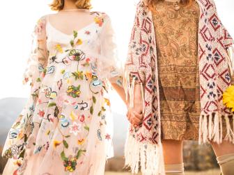 Two boho girls holding each other's hands outdoors