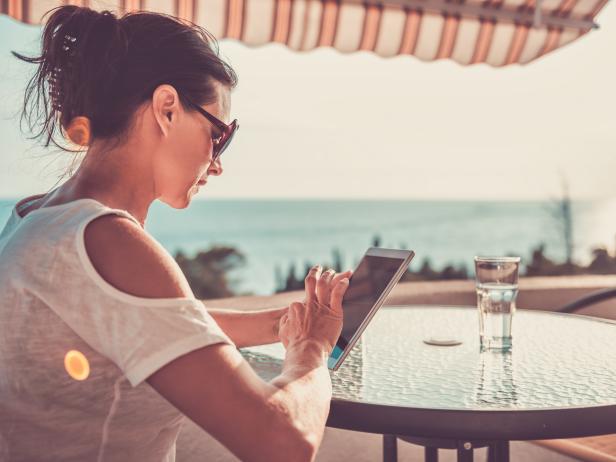 Woman sitting on balcony and using tablet